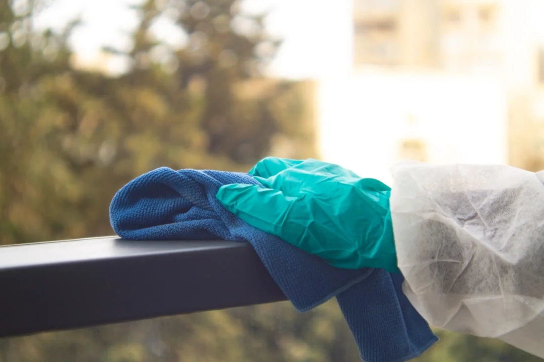 A grown man cleaning a glass window inside, emphasizing domestic cleaning and hygiene.